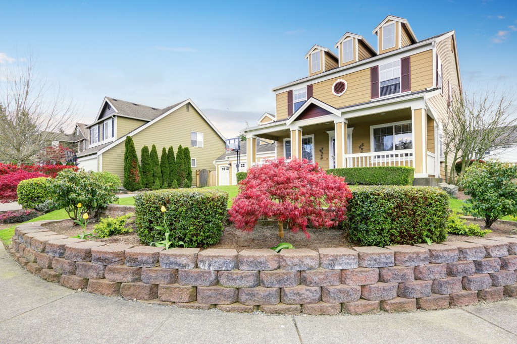 American house exterior with covered porch and columns. Beautiful curb appeal and perfect landscape design. Northwest USA